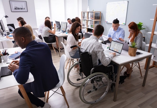 equipe de desenvolvedores trabalhando em um escritório, incluindo um funcionário em cadeira de rodas.