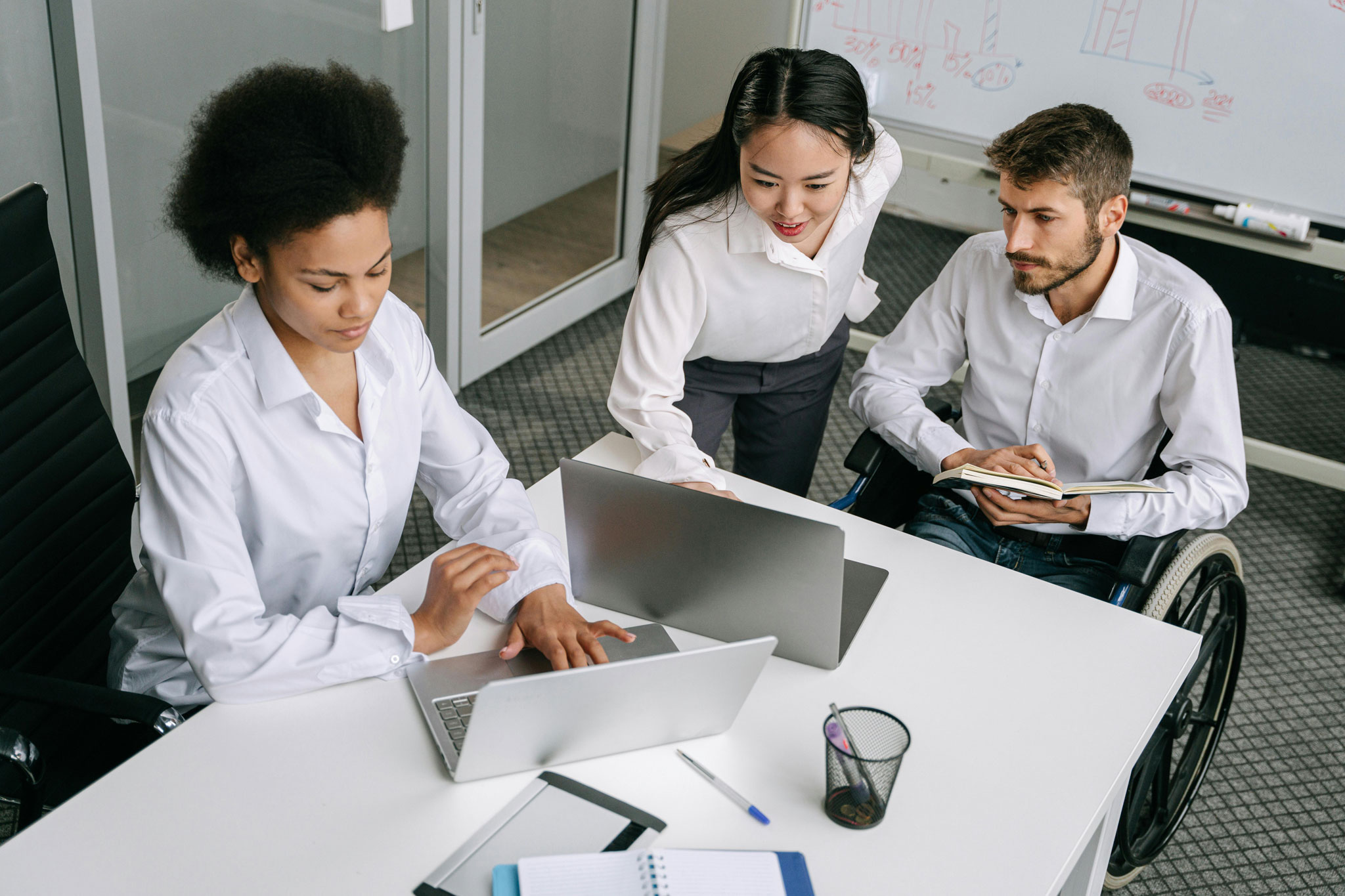 Un grupo de personas, incluyendo una con movilidad reducida, visualizan las tendencias en accesibilidad digital 2025 en una sala de trabajo.