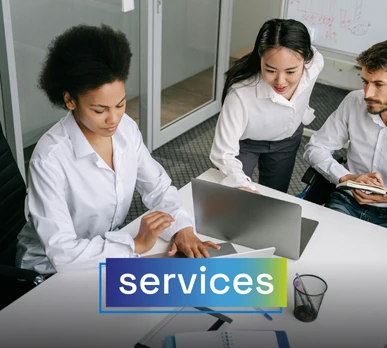 Three people in a business meeting at the office, reviewing information on their laptops. The word "services" is overlaid, representing professional services.
