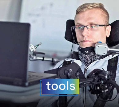 Man with a physical disability using an assisted control system to navigate on his computer. Overlaid text: "tools".