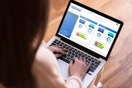 A middle-aged woman seen from behind using a laptop displaying the inSuit 360 platform interface.