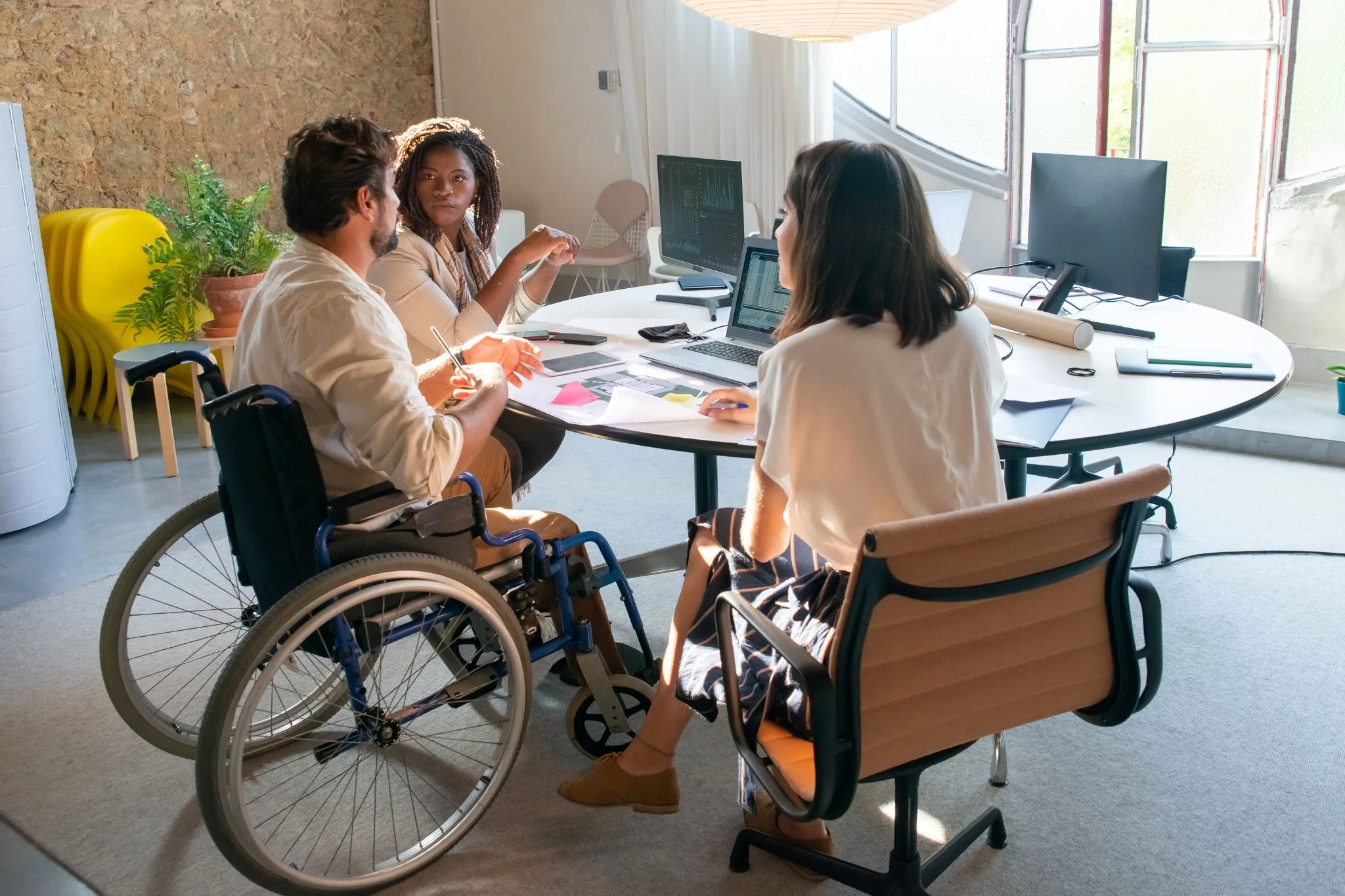Equipo de trabajo conformado por tres personas, una de ellas con movilidad reducida, discuten el Barómetro de Accesibilidad Web 2025.